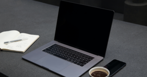 laptop, notes i zegarek leżą na biurku