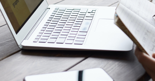 Osoba robi notatki przed monitorem laptopa