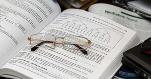 zdjęcie otwartej książki, na której leżą okulary 