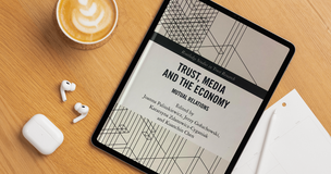 Book titled “Trust, Media and Platforms” next to coffee and writing tools on a desk, representing academic publication.