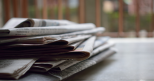 Na stole leżą gazety, jedna na drugiej