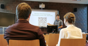 Uczestnicy spotkania tyłem, slajd z kodem QR na rzutniku