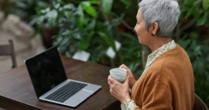 strasza kobieta z kubkiem w dłoni siedząca przed laptopem