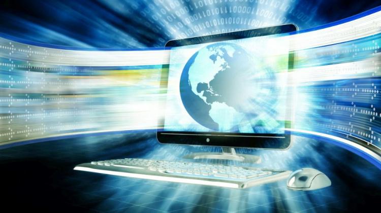 Obrazek przedstawia komputer na granatowym abstrakcyjnym tle.