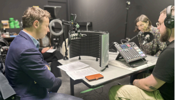Podcast recording session with two speakers using microphones and audio equipment in a studio.