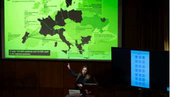 Presenter showing a map of European university alliances on a large screen during a lecture.